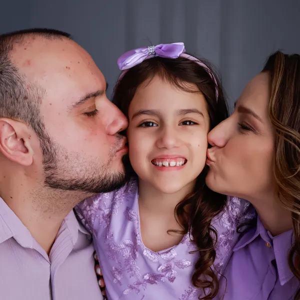Dra. Aline e o marido beijando a filha no rosto