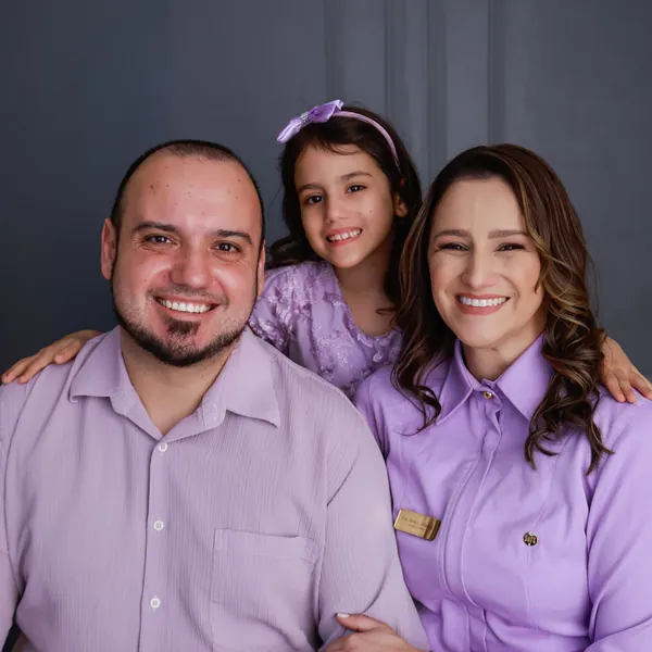 Dra. Aline, o marido e a filha sorrindo juntos