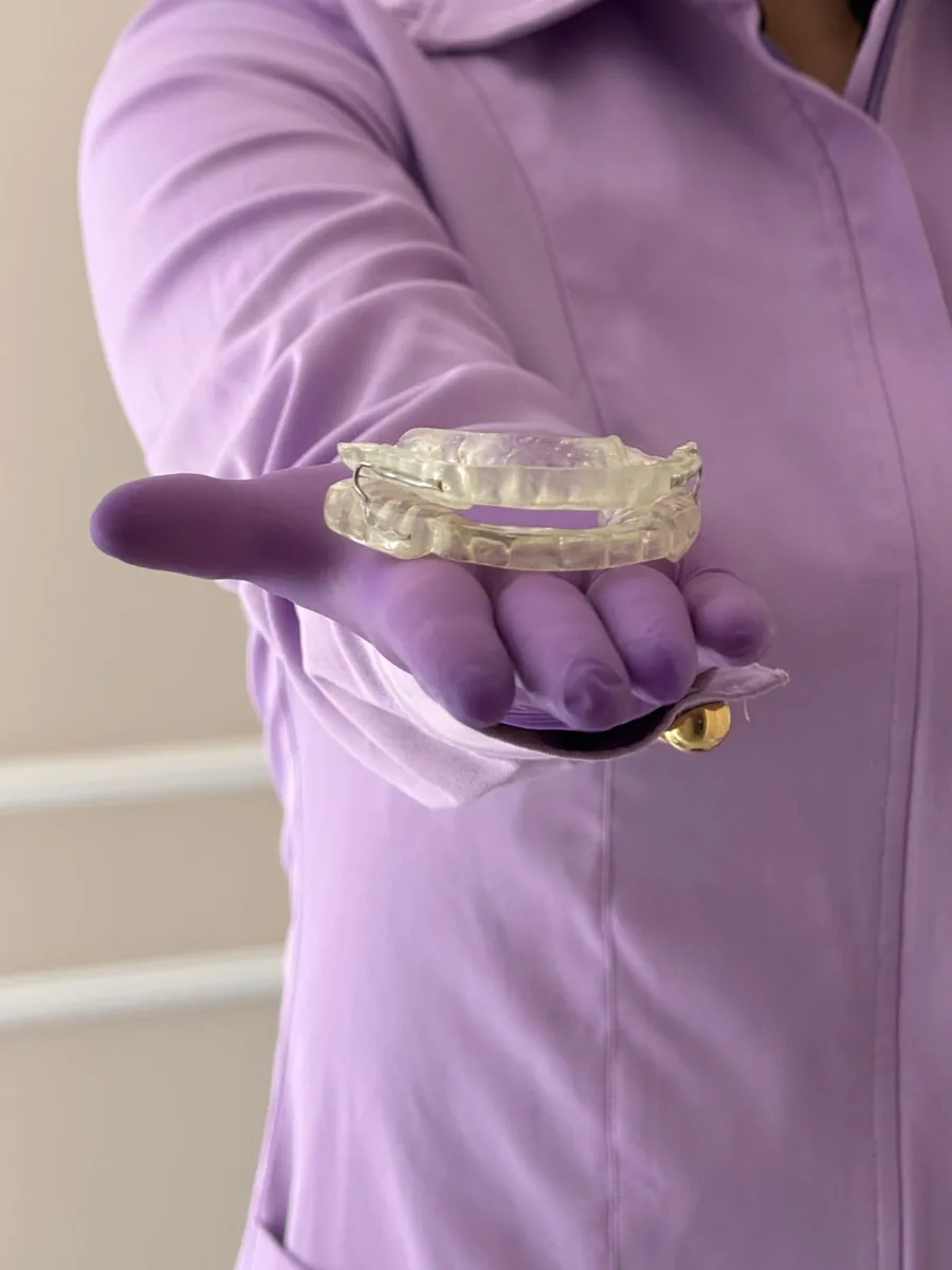 Dra. Aline segurando uma placa transparente para o sono na palma da mão