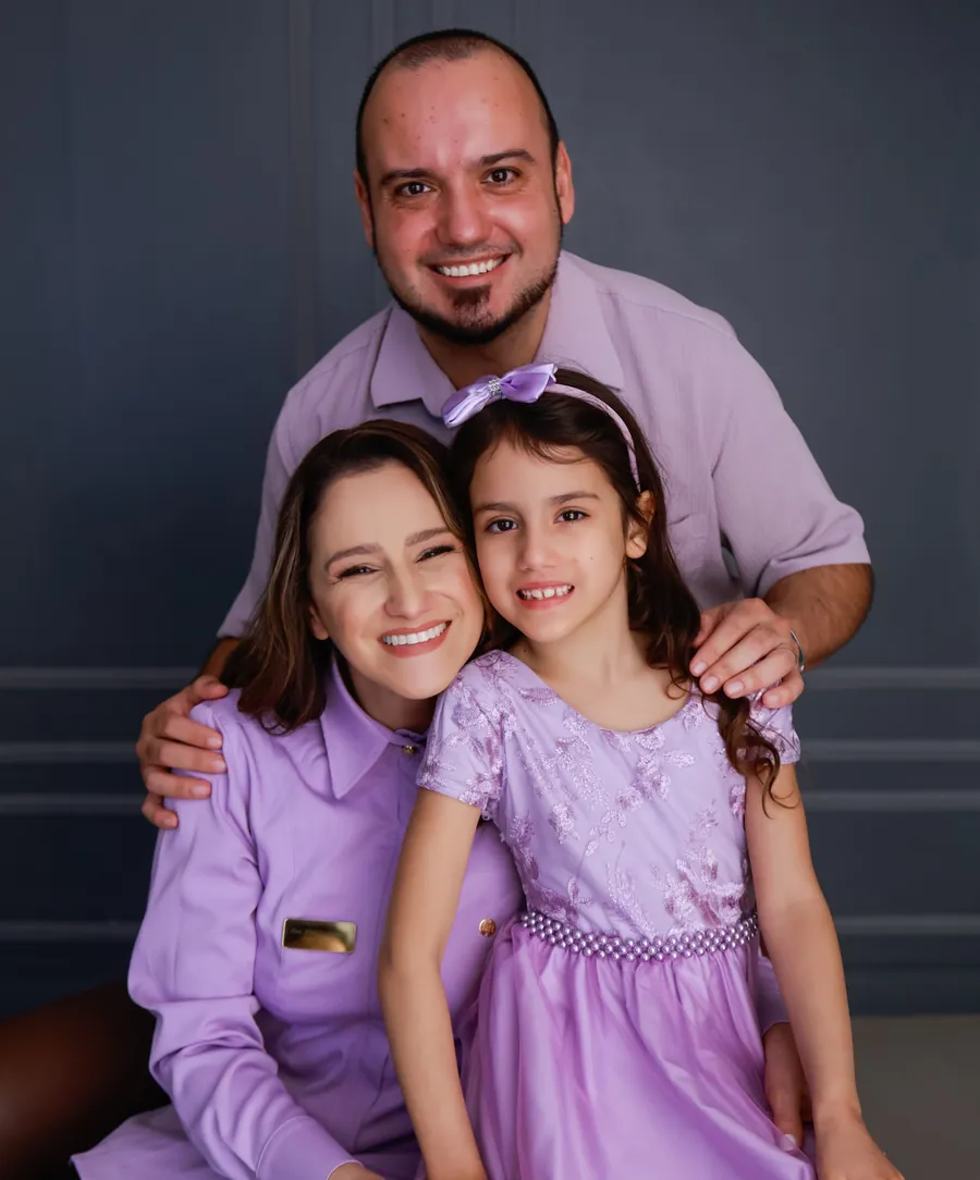 Dra. Aline Struckel com o marido e a filha, todos vestindo lilás